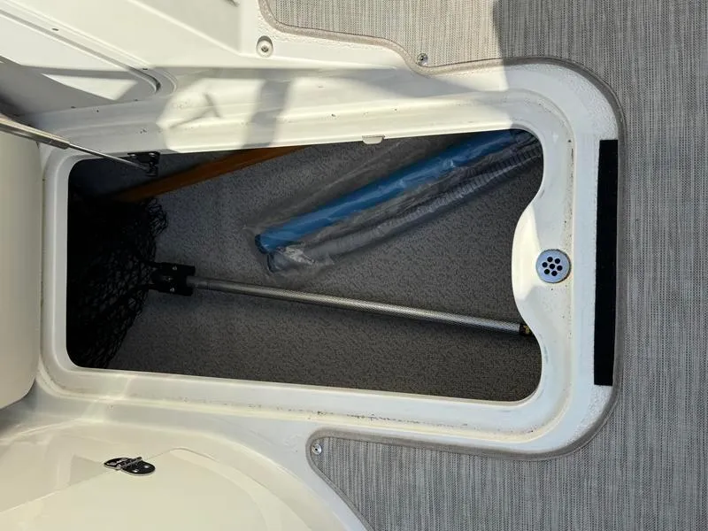 Slide: The Image of Storage compartment in a 2018 Stingray 214 LR boat, featuring a drain and equipment. - 29