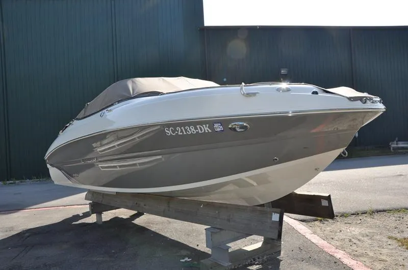 Slide: The Image of 2018 Stingray 214 LR boat on display, gray and white exterior, parked on a wooden stand. - 6