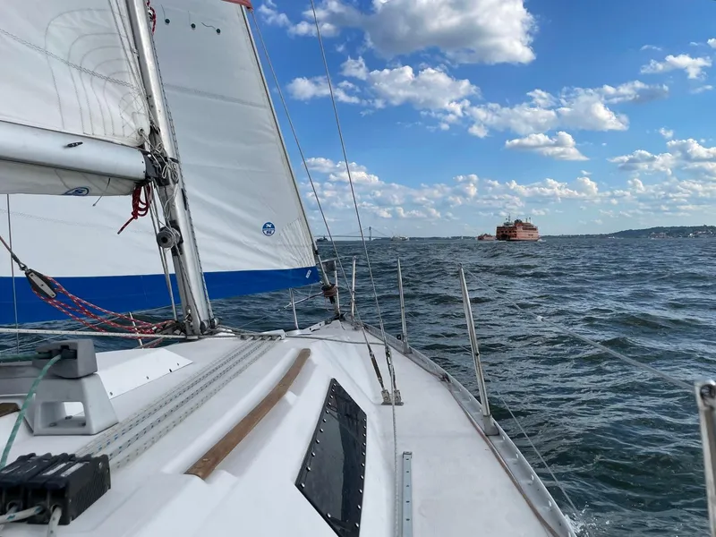 Slide: The Image of Sailing on a 1990 Beneteau First 285 with a ferry in the distance, under a blue sky. - 9