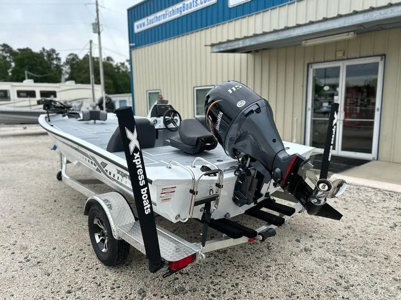 Slide: The Image of 2025 Xpress H18 Bass boat with motor on trailer outside dealership. - 2