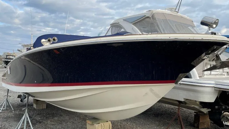 Slide: The Image of 2017 Chris-Craft Launch 28 boat on stands, blue hull with red stripe, cloudy sky background. - 3