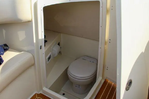 Slide: The Image of 2017 Chris-Craft Launch 28 boat interior with compact marine toilet and beige seating. - 8