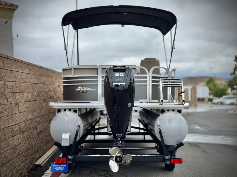 Slide: The Image of 2023 Sun Tracker Party Barge 20 DLX pontoon boat with outboard motor, parked on trailer. - 4