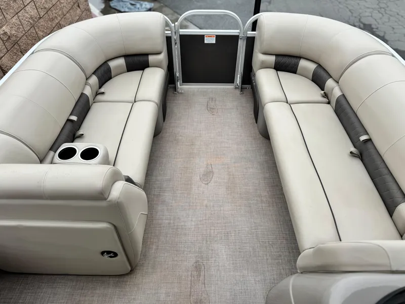Slide: The Image of 2023 Sun Tracker Party Barge 20 DLX interior with beige seating and cup holders. - 8