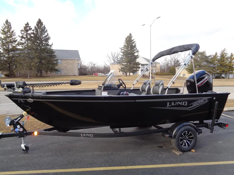 The Image of 2025 Lund 1650 Rebel XL SS boat on trailer, parked outdoors, side view. - 0
