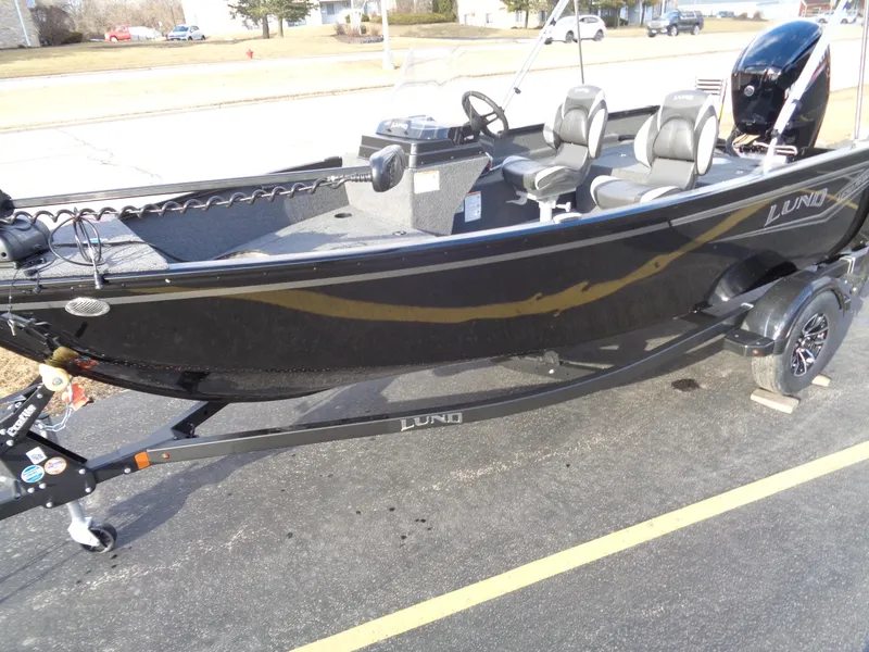 Slide: The Image of 2025 Lund 1650 Rebel XL SS boat on trailer, black exterior, parked outdoors. - 2