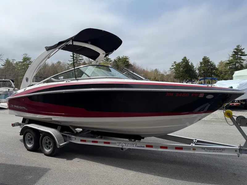 Slide: The Image of 2016 Regal 2300 Bowrider boat on trailer, black and red design, parked outdoors. - 2