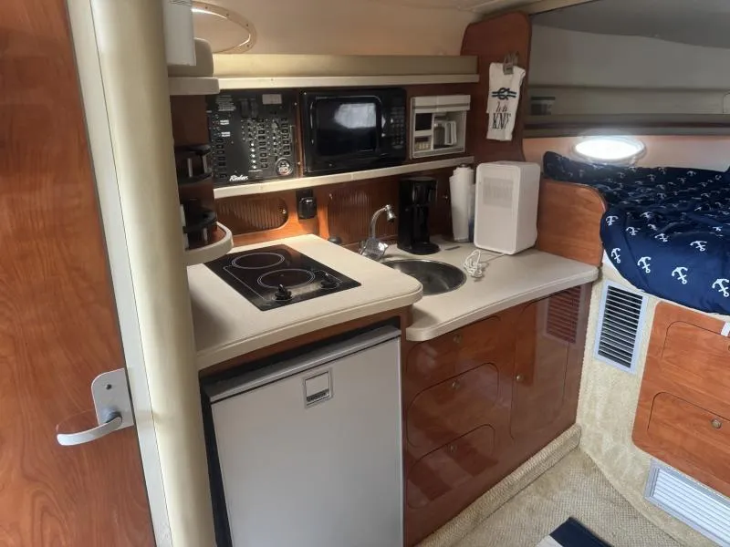 Slide: The Image of 2004 Rinker 342 Fiesta Vee cabin kitchen with stove, microwave, and compact fridge. - 16