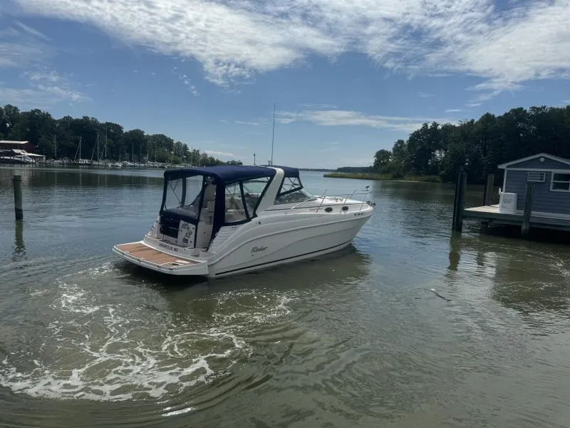Slide: The Image of 2004 Rinker 342 Fiesta Vee boat on calm water near a dock, under a partly cloudy sky. - 6