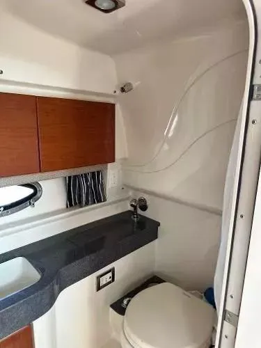Slide: The Image of 2012 Formula 350 SS boat bathroom with sink, toilet, and wooden cabinets. - 16