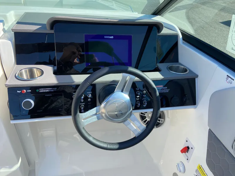 Slide: The Image of 2023 Sea Ray SDX 250 helm with steering wheel, digital display, and cup holders. - 9