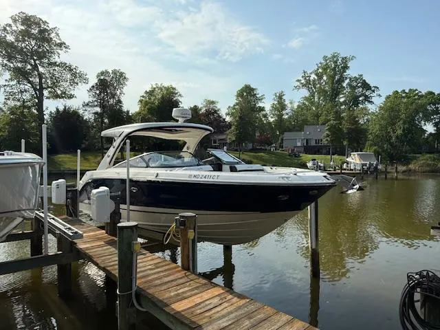 Slide: The Image of 2018 Sea Ray SLX 310 boat docked on a serene lake with trees in the background. - 0