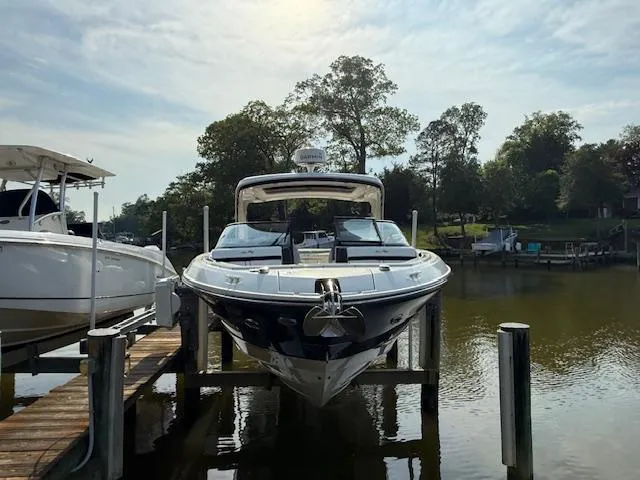 Slide: The Image of 2018 Sea Ray SLX 310 boat docked on a sunny day, surrounded by trees. - 1
