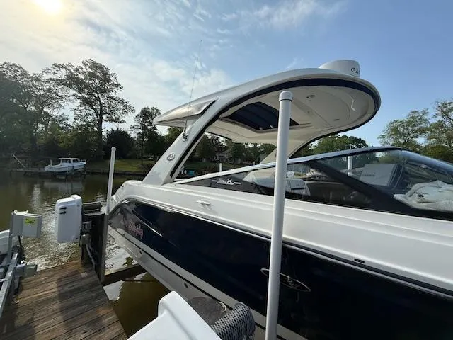 Slide: The Image of 2018 Sea Ray SLX 310 boat docked by a serene lakeside under a clear sky. - 2