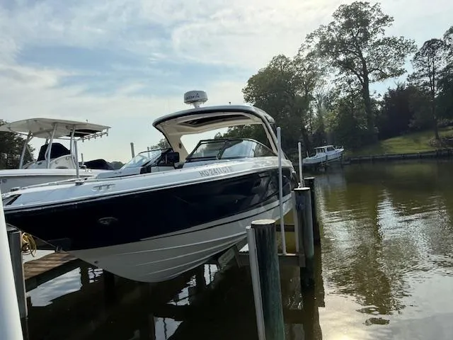 Slide: The Image of 2018 Sea Ray SLX 310 boat docked on a calm lake with trees in the background. - 3