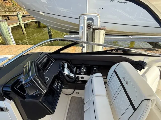 Slide: The Image of 2018 Sea Ray SLX 310 boat interior with helm and seating, docked near water. - 6