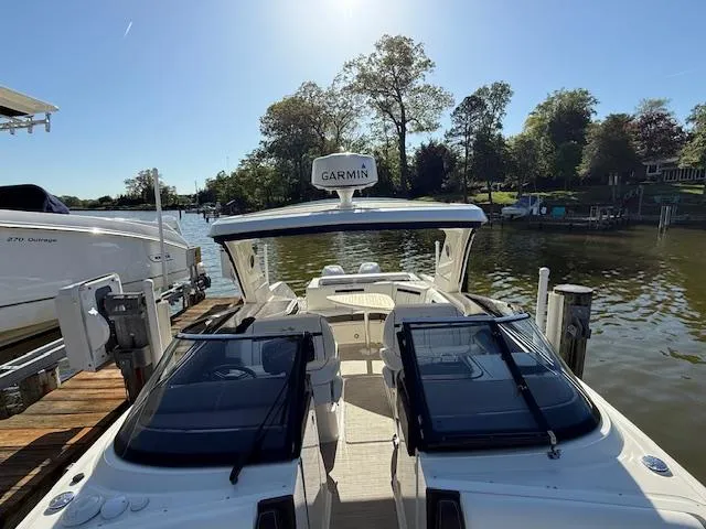 Slide: The Image of 2018 Sea Ray SLX 310 boat docked by a serene lakeside with clear skies. - 8