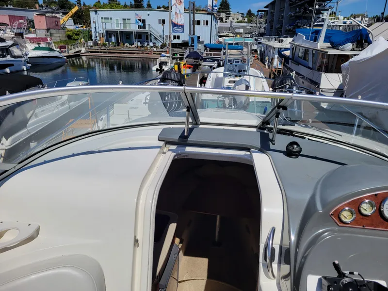 Slide: The Image of 2005 Bayliner 265 boat interior view at marina, showcasing helm and cabin entrance. - 16