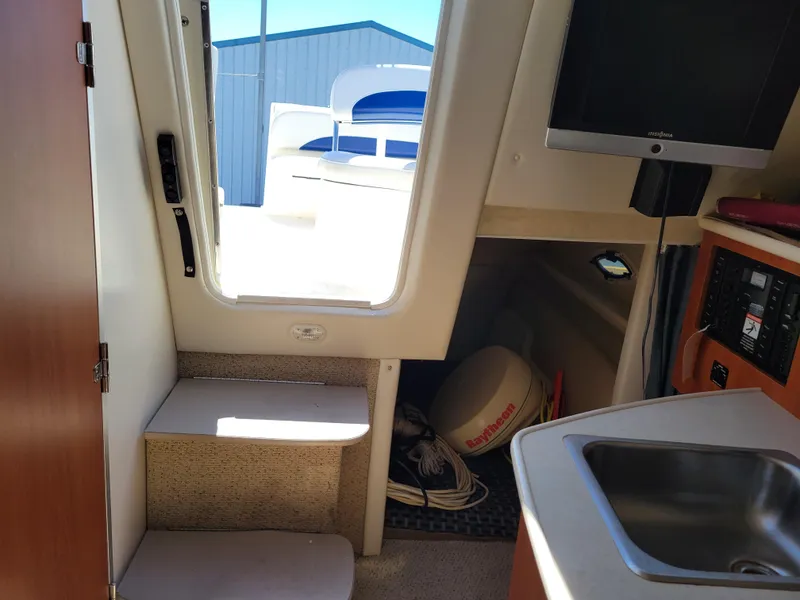 Slide: The Image of Interior of a 2005 Bayliner 265 boat, featuring a sink, steps, and a small TV. - 19