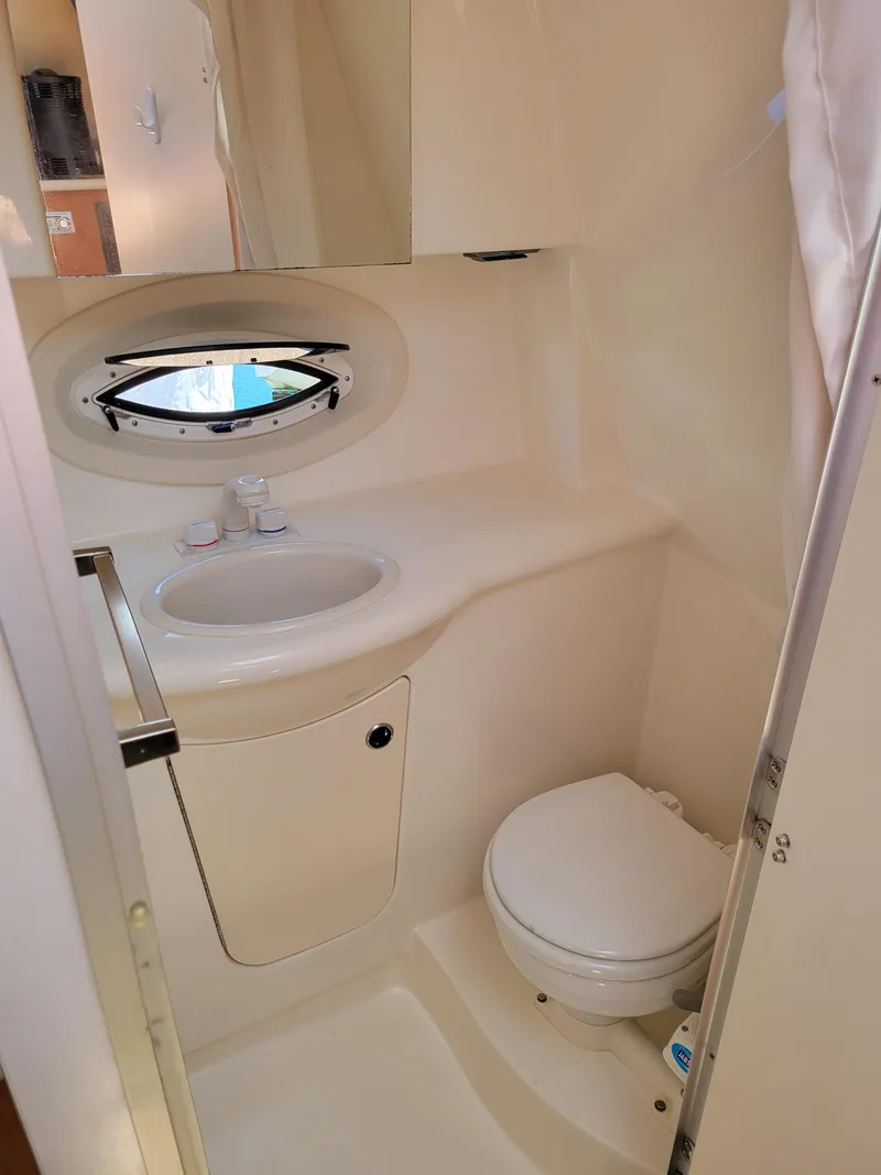 Slide: The Image of 2005 Bayliner 265 boat bathroom with sink, toilet, and porthole window. - 27