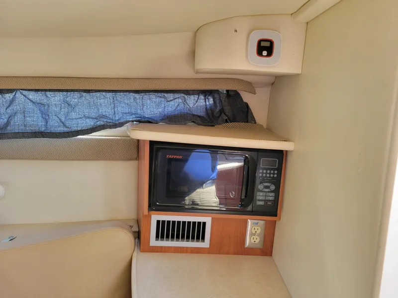 Slide: The Image of 2005 Bayliner 265 interior with microwave, power outlet, and window curtain. - 30