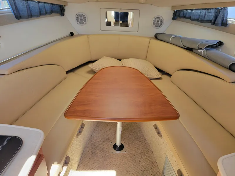 Slide: The Image of 2005 Bayliner 265 cabin interior with beige seating and wooden table. - 31