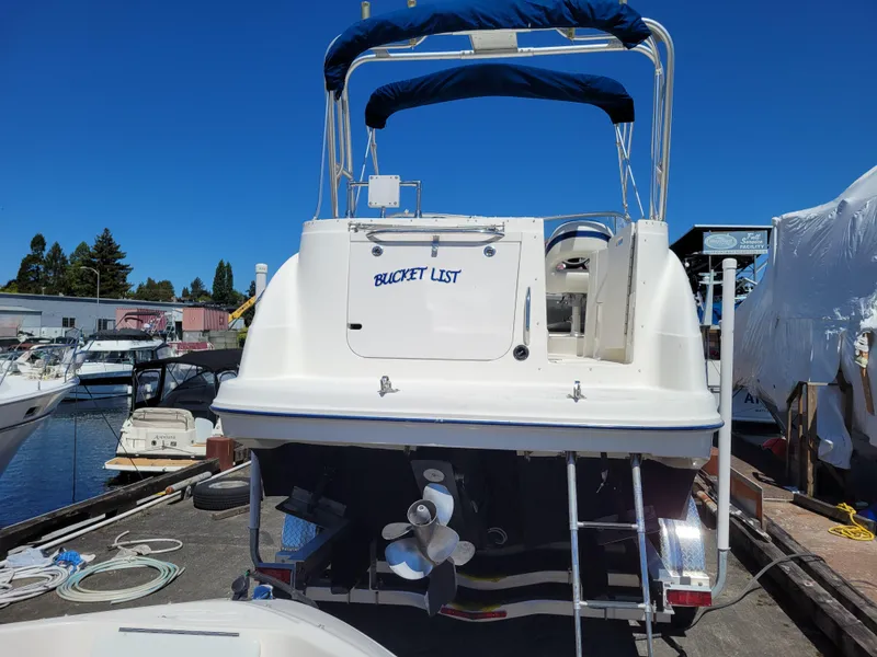 Slide: The Image of 2005 Bayliner 265 boat docked, rear view with "Bucket List" text, sunny day. - 4