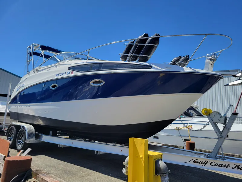 Slide: The Image of 2005 Bayliner 265 boat on trailer, blue and white hull, docked outdoors. - 6