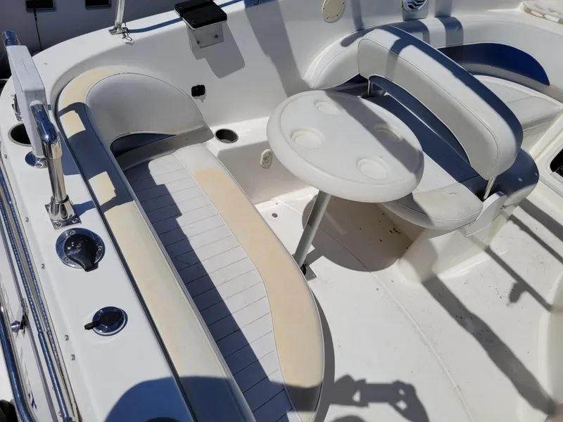Slide: The Image of 2005 Bayliner 265 boat interior with seating and table, featuring white and blue upholstery. - 9