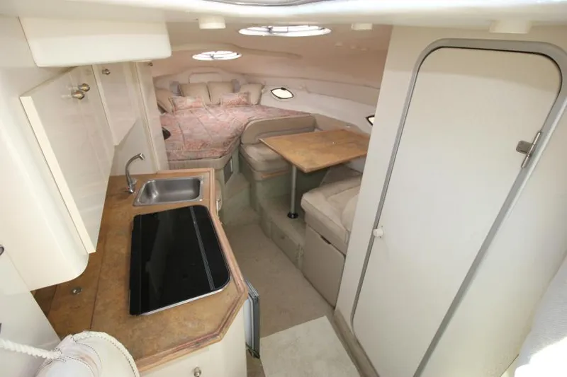 Slide: The Image of 1999 Maxum 2800 SCR cabin interior with kitchenette, seating, and sleeping area. - 12