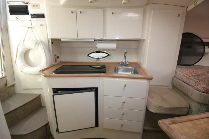 Slide: The Image of 1999 Maxum 2800 SCR boat interior with kitchenette, sink, and compact fridge. - 15