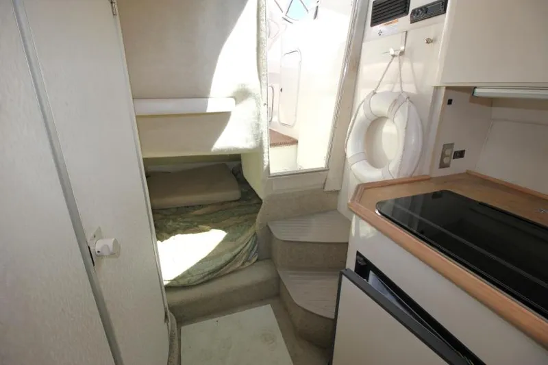 Slide: The Image of Interior of 1999 Maxum 2800 SCR boat, featuring compact kitchen and cozy sleeping area. - 16
