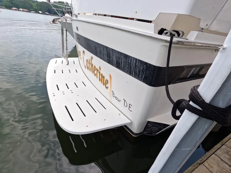 Slide: The Image of 1988 Viking Gulfstar 55 MY yacht docked, featuring a white swim platform and black stripe. - 20