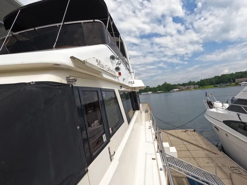 Slide: The Image of 1988 Viking Gulfstar 55 MY yacht docked by a serene lake under a partly cloudy sky. - 38