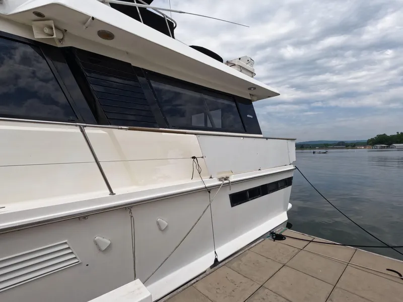 Slide: The Image of 1988 Viking Gulfstar 55 MY yacht docked by a serene lake under cloudy skies. - 5