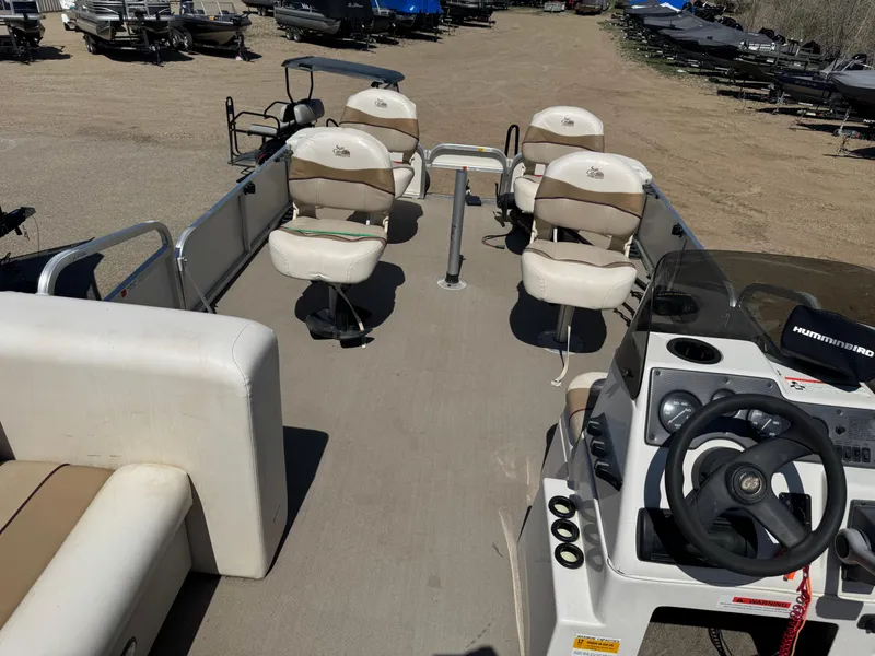 Slide: The Image of 2008 G3 SunCatcher 228 F&C Vinyl boat with seating and steering console, parked on sandy ground. - 16