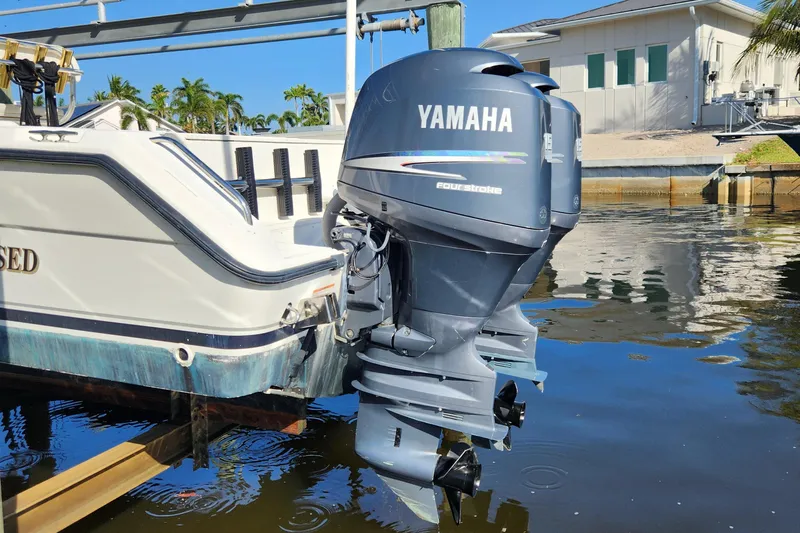 Slide: The Image of 2004 Pursuit 2470 Center Console with Yamaha outboard motor docked by waterfront home. - 23