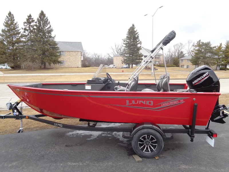 The Image of 2025 Lund 1650 Rebel XL SS boat in red, parked on a trailer outdoors. - 0