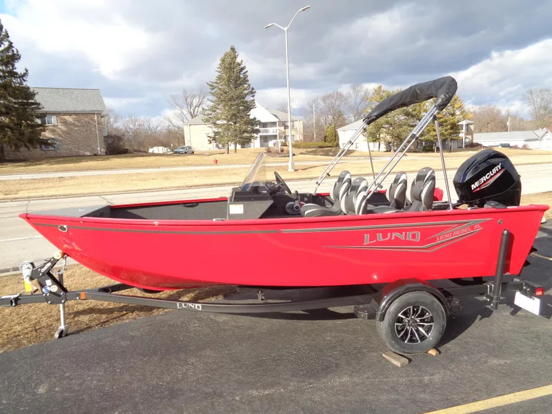 Slide: The Image of 2025 Lund 1650 Rebel XL SS boat, red exterior, on trailer, parked outdoors. - 1