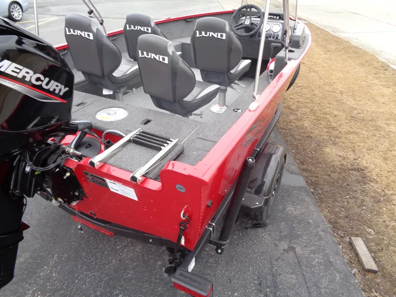 Slide: The Image of 2025 Lund 1650 Rebel XL SS boat, red exterior, Mercury engine, four seats, docked on pavement. - 13