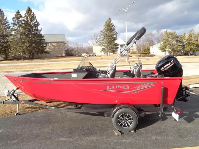Slide: The Image of 2025 Lund 1650 Rebel XL SS boat, red, on trailer, parked outdoors. - 17