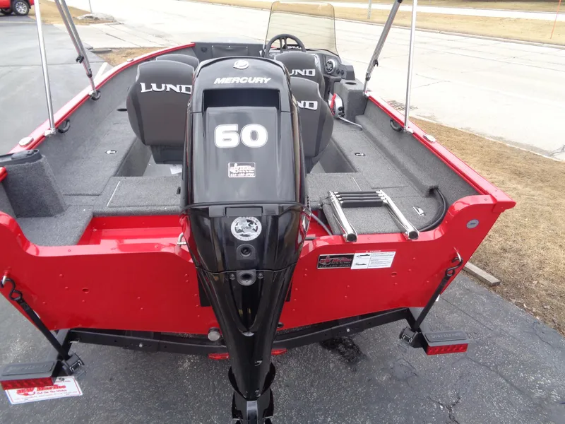 Slide: The Image of 2025 Lund 1650 Rebel XL SS boat with Mercury 60 engine, red exterior, parked on pavement. - 2