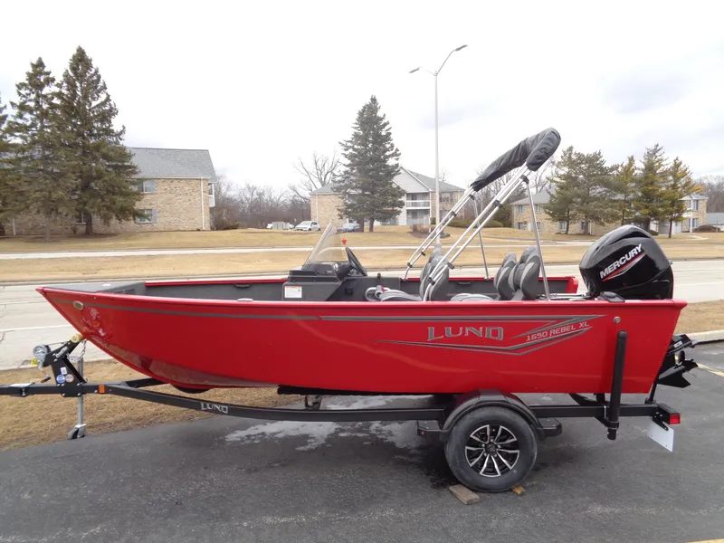 Slide: The Image of 2025 Lund 1650 Rebel XL SS boat, red, on trailer, parked outdoors. - 7