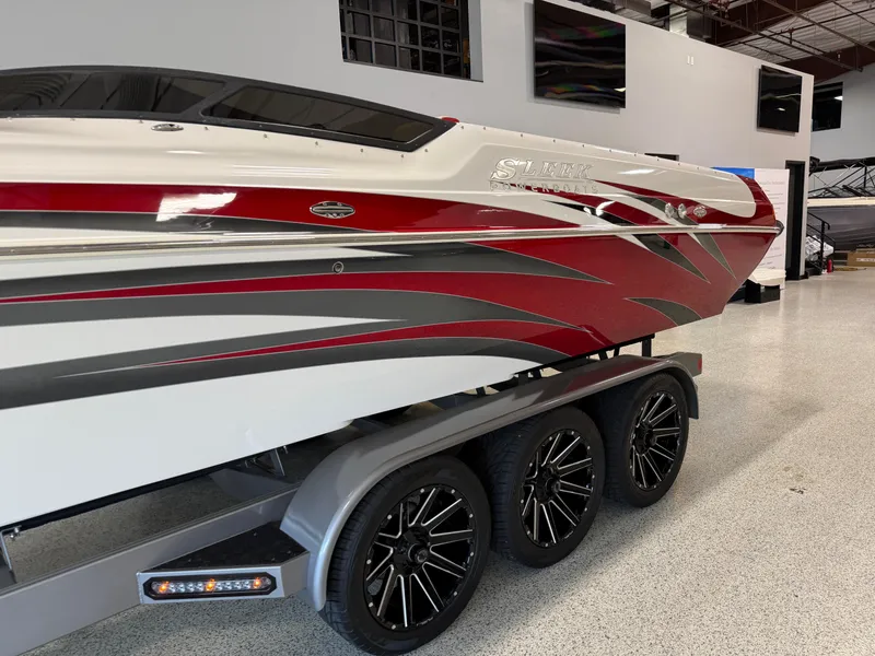 Slide: The Image of 2006 Sleekcraft Heritage boat with red and gray design on a triple-axle trailer. - 3