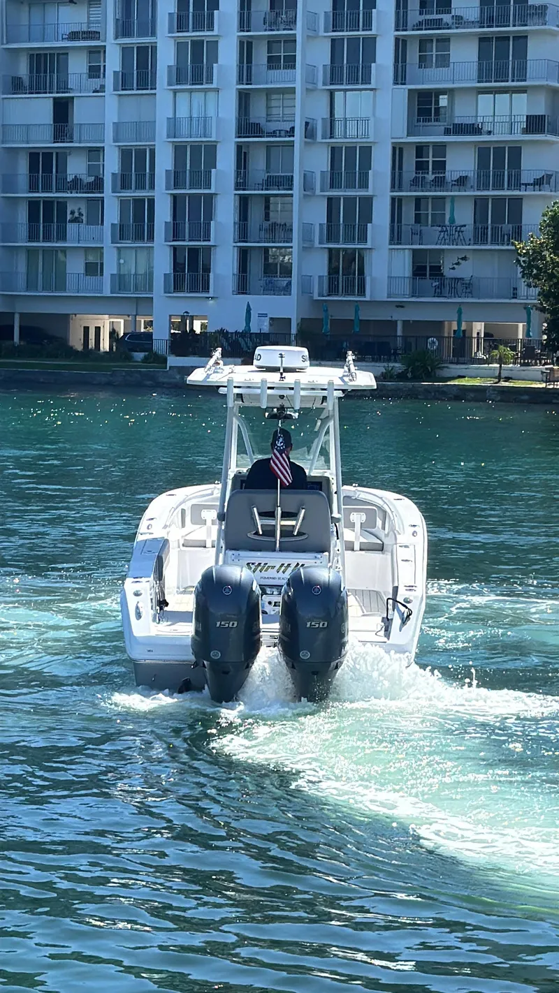 Slide: The Image of A 2021 Release 240 RX boat cruising on water near modern waterfront buildings. - 1