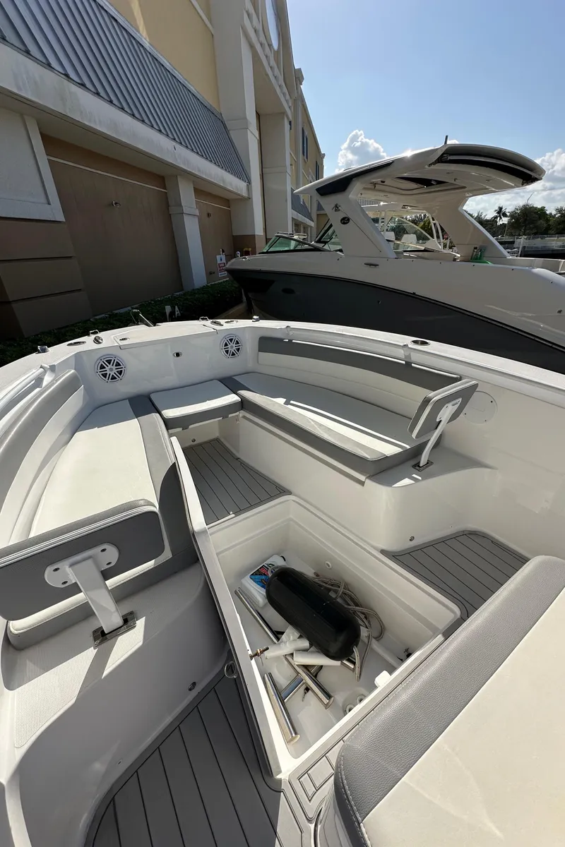 Slide: The Image of 2021 Release 240 RX boat interior with seating and storage, docked near a building. - 25