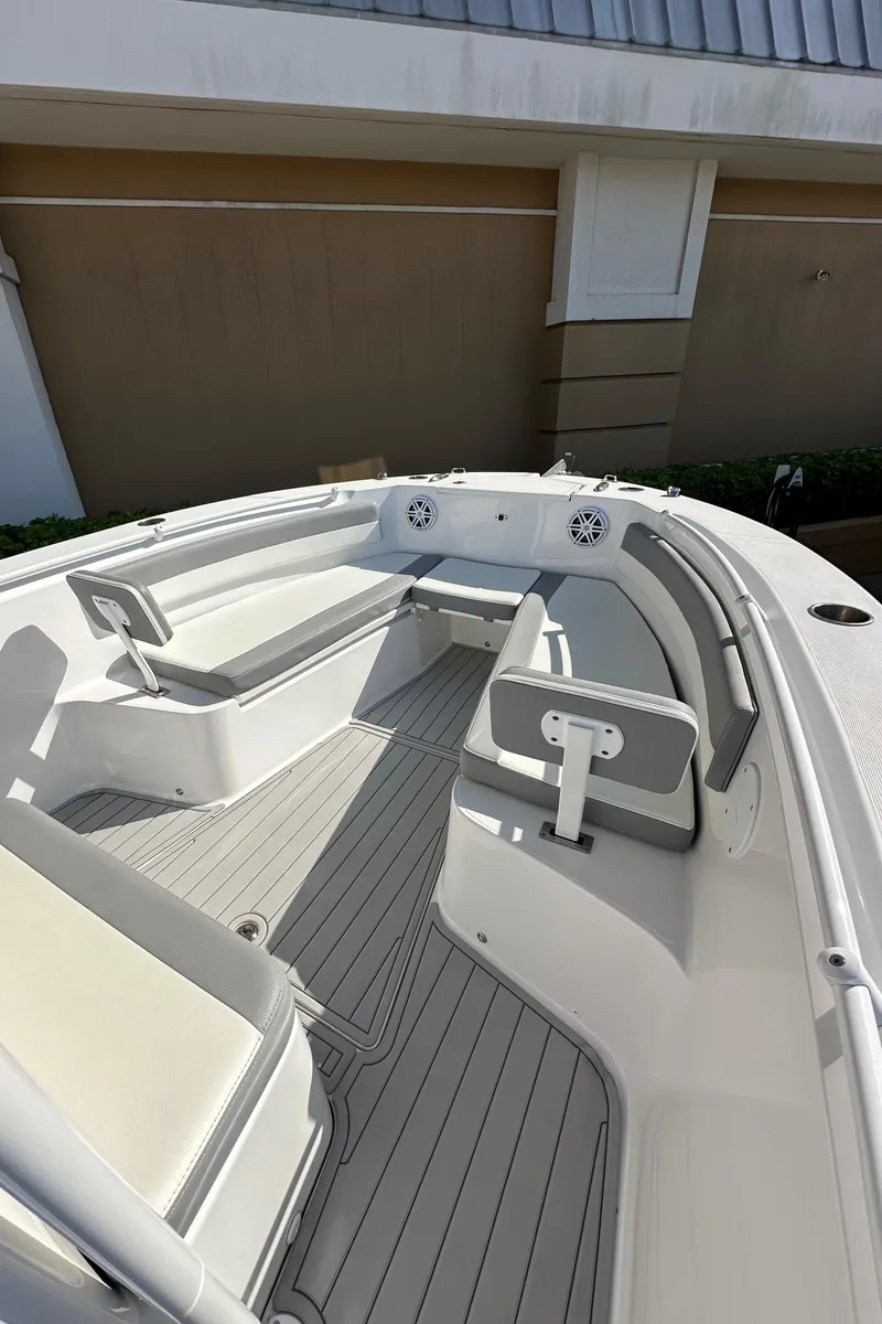 Slide: The Image of 2021 Release 240 RX boat interior with seating and speakers, docked near a building. - 26