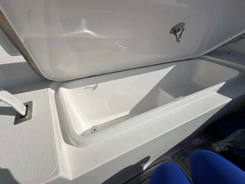 Slide: The Image of Open storage compartment on a 2021 Release 240 RX boat, featuring a sleek white interior. - 28