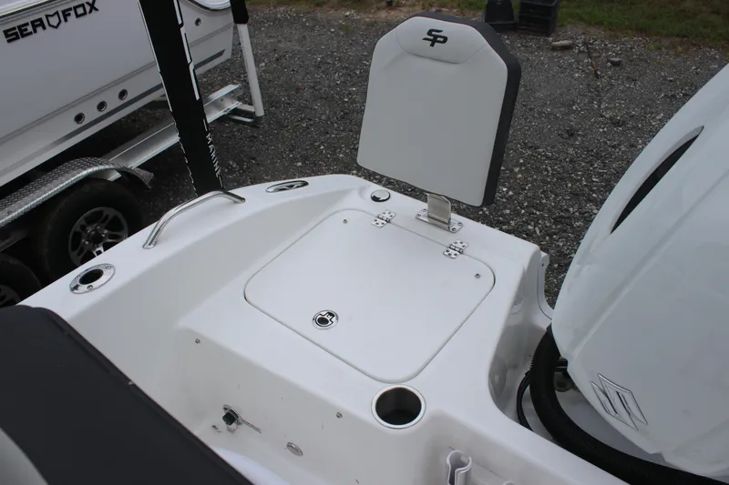 Slide: The Image of 2025 Sea Pro 202 CC boat stern with seating and motor, parked on gravel. - 16