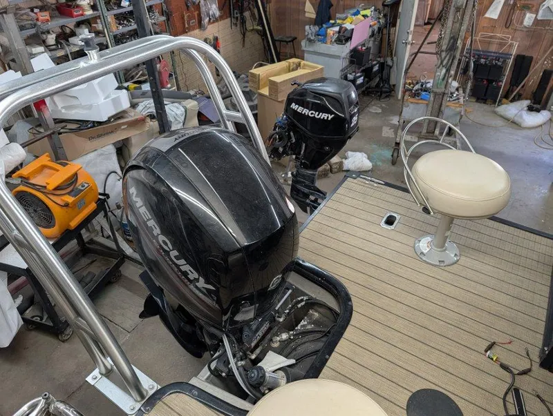 Slide: The Image of 2018 Sylvan Mirage Cruise 8524 Entertainer boat with Mercury outboard motors in a workshop. - 13